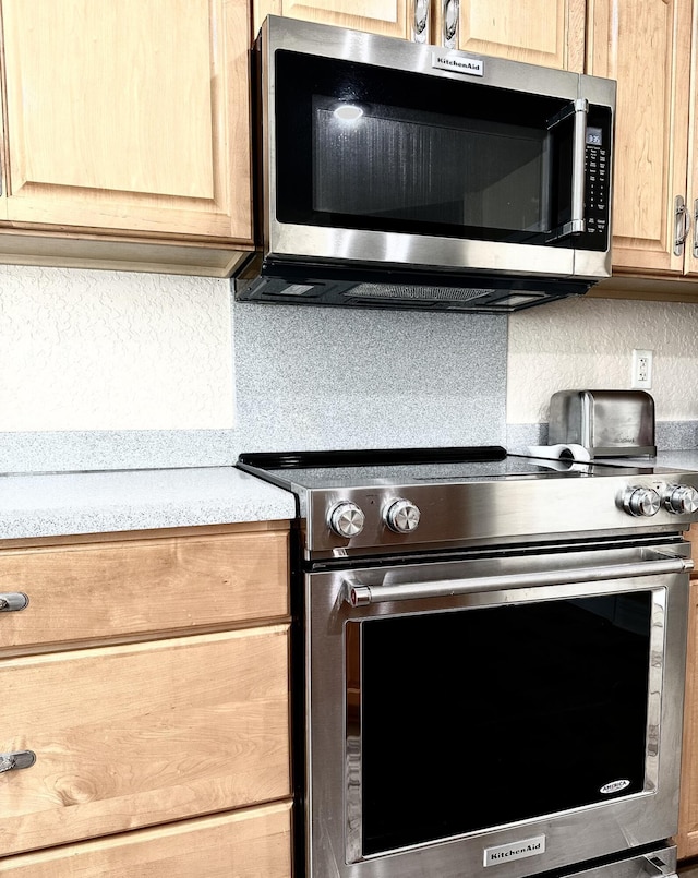 interior details featuring decorative backsplash and appliances with stainless steel finishes