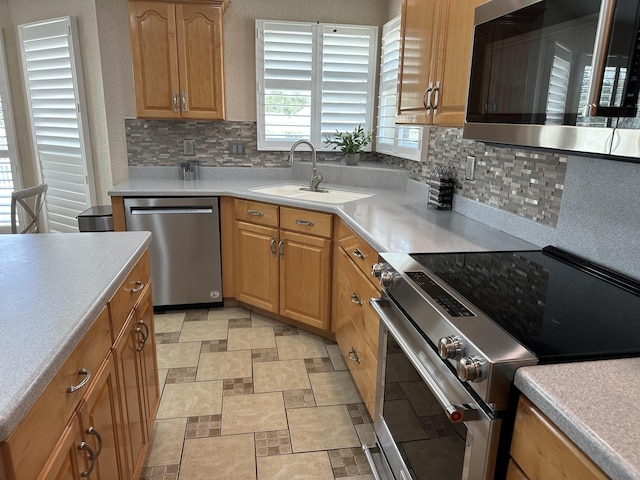 kitchen featuring tasteful backsplash, stone finish flooring, light countertops, appliances with stainless steel finishes, and a sink