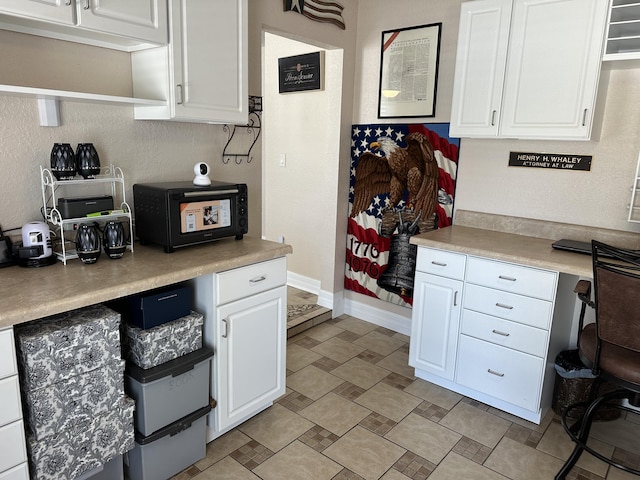 kitchen featuring white cabinetry, light countertops, and baseboards