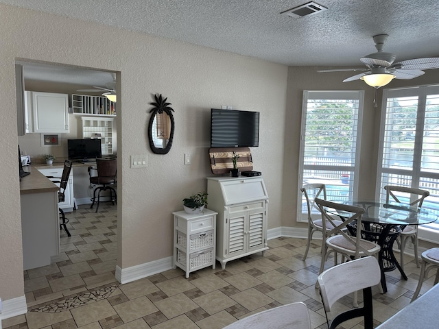 dining area with baseboards, visible vents, ceiling fan, a textured ceiling, and a textured wall