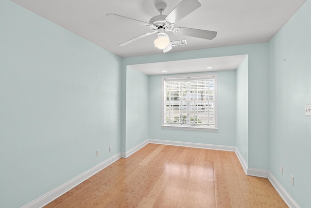 empty room with a ceiling fan, visible vents, baseboards, and wood finished floors