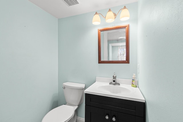 half bathroom with toilet, vanity, and visible vents