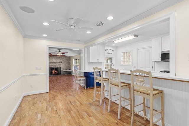 kitchen with visible vents, stainless steel microwave, a breakfast bar area, blue cabinetry, and white cabinetry