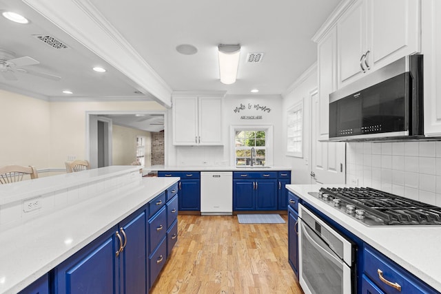 kitchen featuring stainless steel appliances, a sink, visible vents, light countertops, and blue cabinetry