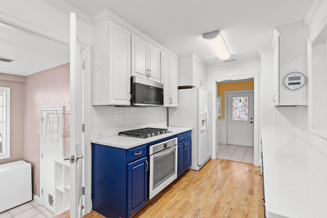 kitchen with blue cabinetry, appliances with stainless steel finishes, white cabinets, and light countertops