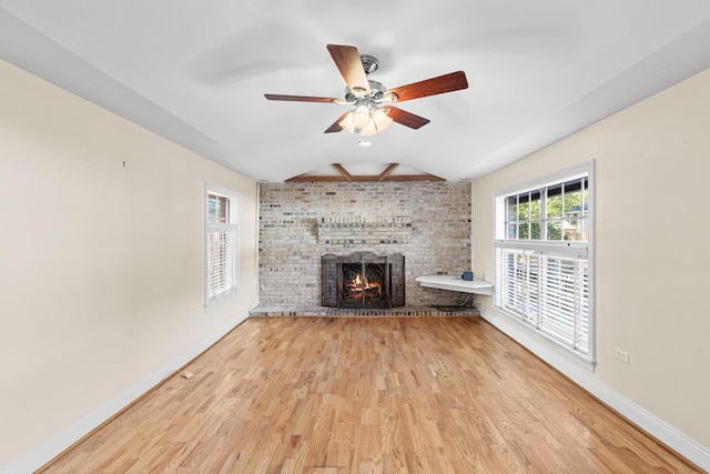 unfurnished living room featuring lofted ceiling, a ceiling fan, a brick fireplace, wood finished floors, and baseboards