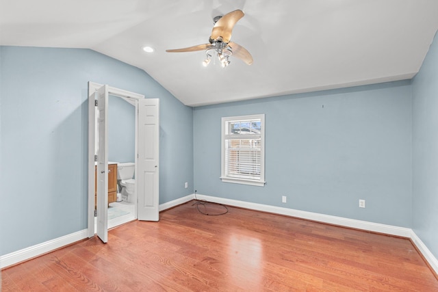 unfurnished bedroom with vaulted ceiling, ensuite bathroom, wood finished floors, and baseboards