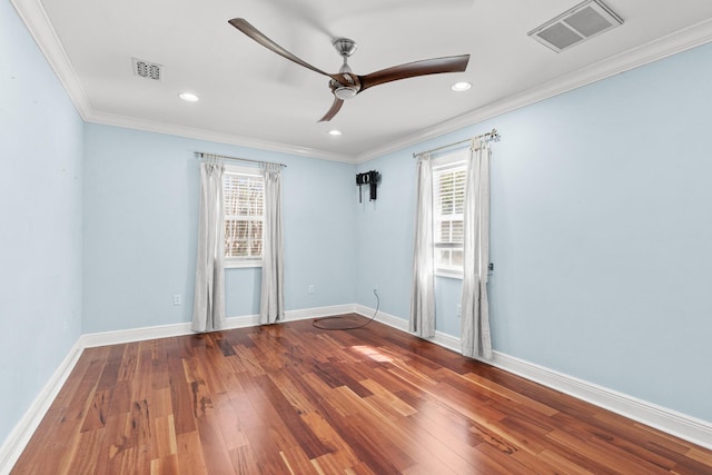 empty room featuring a wealth of natural light, wood-type flooring, and visible vents