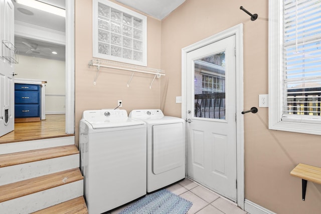 laundry room with laundry area, washing machine and dryer, baseboards, and light tile patterned flooring