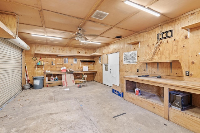 misc room featuring ceiling fan, a workshop area, unfinished concrete flooring, and visible vents