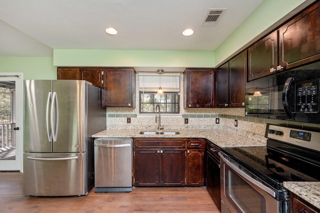 kitchen featuring visible vents, light wood-style flooring, stainless steel appliances, dark brown cabinets, and a sink