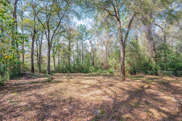 view of yard featuring fence and a forest view