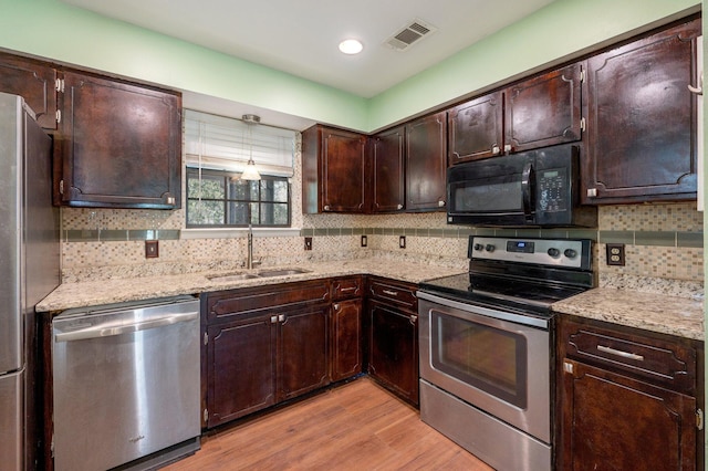 kitchen with dark brown cabinetry, light wood finished floors, visible vents, stainless steel appliances, and a sink