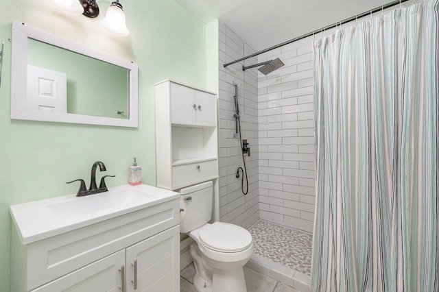 bathroom featuring toilet, tile patterned flooring, a tile shower, and vanity