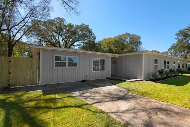 view of front facade featuring a patio area, concrete driveway, a front yard, and fence