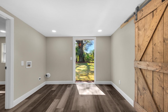 doorway to outside featuring dark wood-type flooring, baseboards, and a barn door