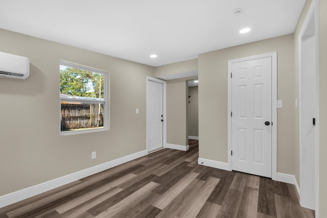 spare room with recessed lighting, baseboards, wood finished floors, and a wall mounted air conditioner