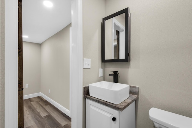 bathroom featuring vanity, wood finished floors, toilet, and baseboards