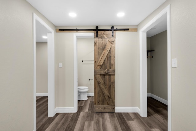 bathroom with toilet, baseboards, and wood finished floors