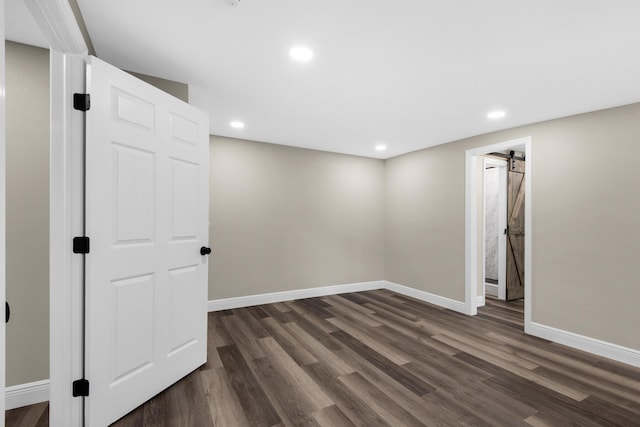 below grade area featuring a barn door, recessed lighting, dark wood finished floors, and baseboards