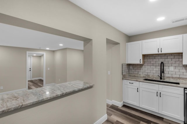 kitchen featuring white cabinetry, a sink, decorative backsplash, and wood finished floors