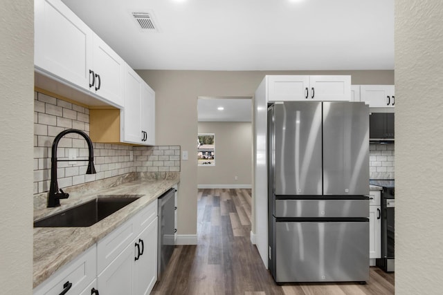 kitchen with light stone counters, visible vents, appliances with stainless steel finishes, dark wood-type flooring, and a sink