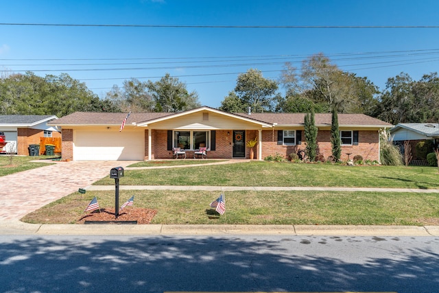 view of front facade with decorative driveway, a front yard, an attached garage, and brick siding