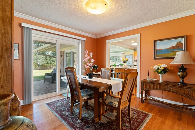 dining room featuring a textured ceiling, light wood-style floors, and ornamental molding