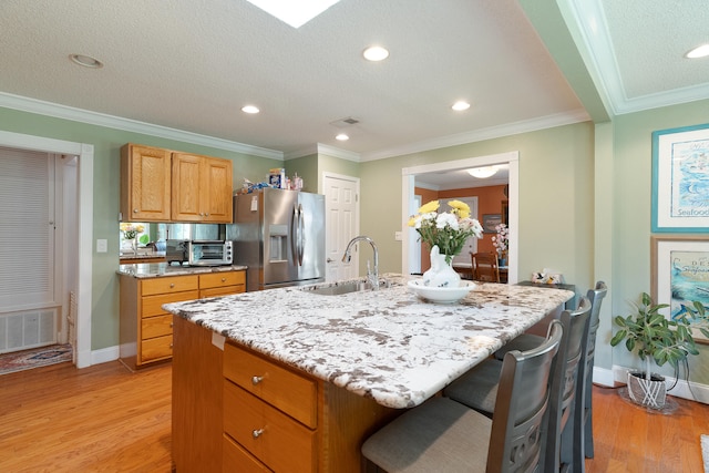 kitchen featuring a sink, visible vents, light wood-style flooring, and stainless steel fridge with ice dispenser