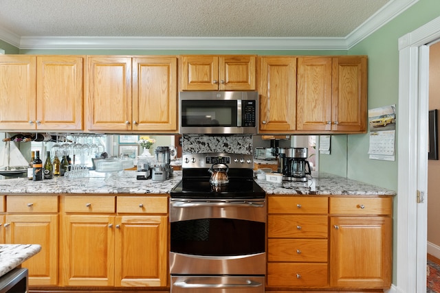 kitchen with stainless steel appliances, light stone countertops, a textured ceiling, and ornamental molding