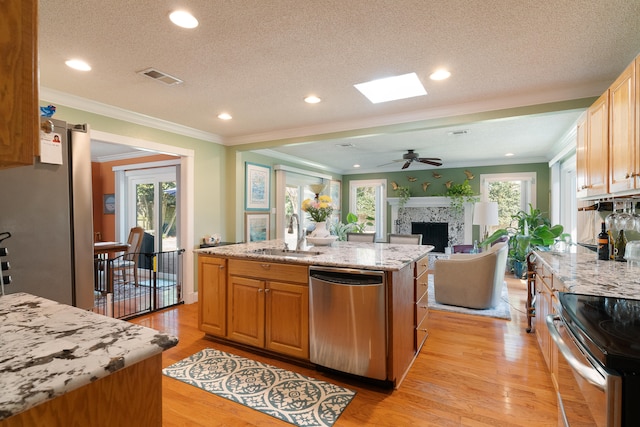 kitchen featuring visible vents, an island with sink, light wood-style flooring, stainless steel appliances, and a sink