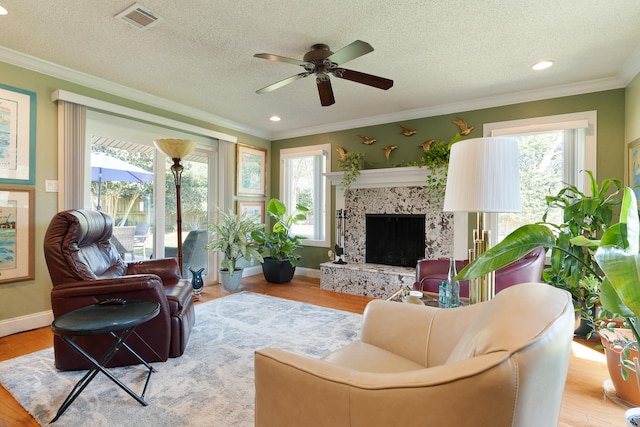 living room featuring visible vents, crown molding, ceiling fan, and wood finished floors