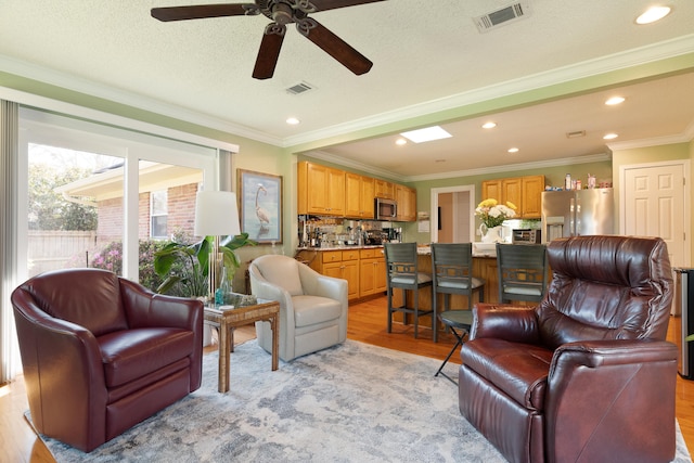 living room with visible vents, light wood-style floors, and ceiling fan