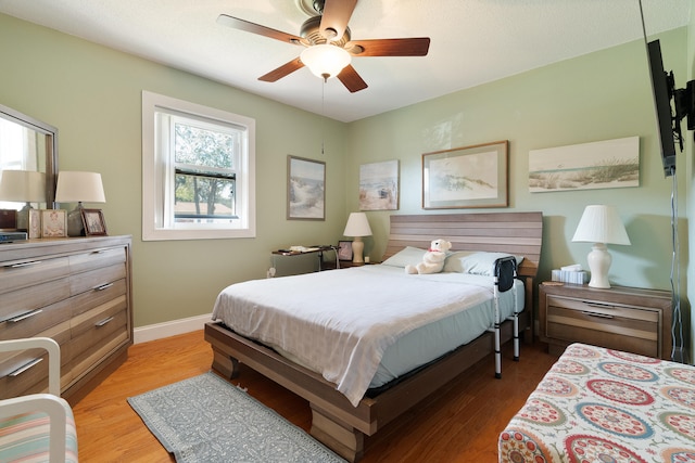 bedroom with a ceiling fan, light wood-type flooring, and baseboards