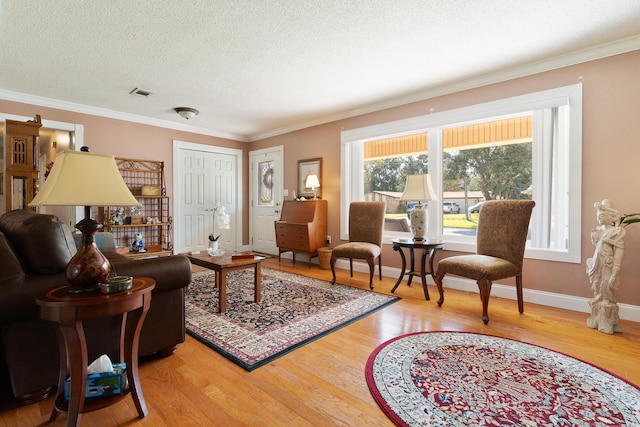 living room with visible vents, baseboards, a textured ceiling, and light wood finished floors