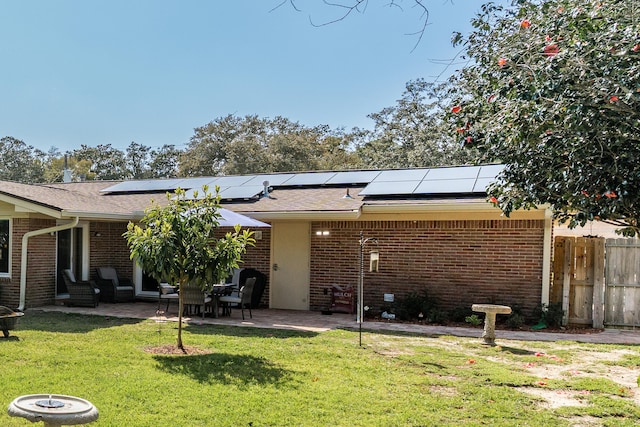 back of property featuring brick siding, a lawn, a patio, and fence