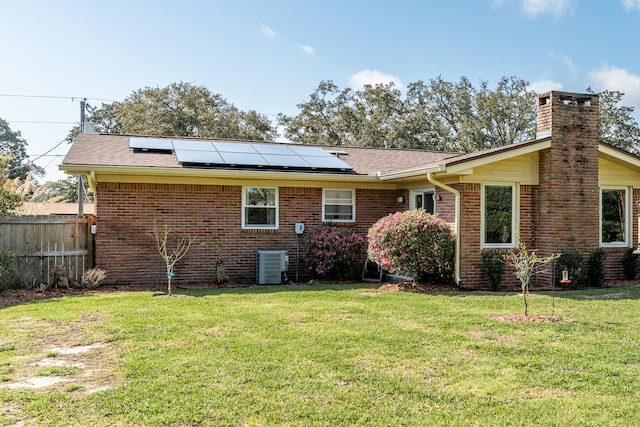 rear view of property featuring a lawn, brick siding, and fence