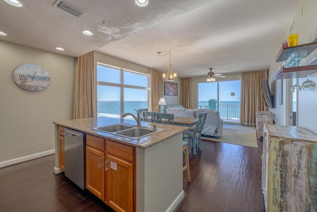 kitchen with a sink, visible vents, open floor plan, stainless steel dishwasher, and dark wood-style floors