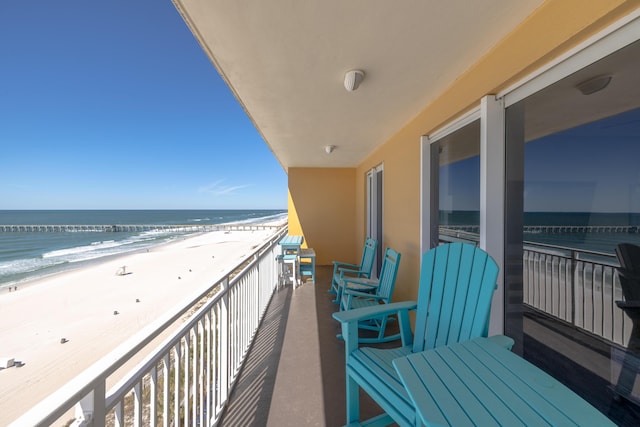 balcony with a water view and a view of the beach