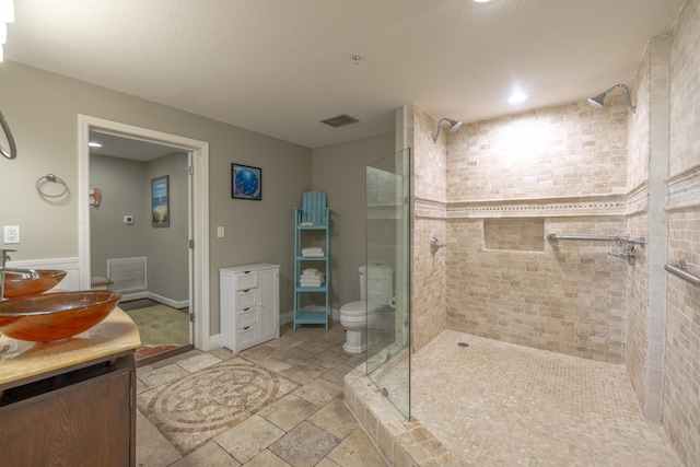 bathroom with a stall shower, stone tile floors, visible vents, and vanity