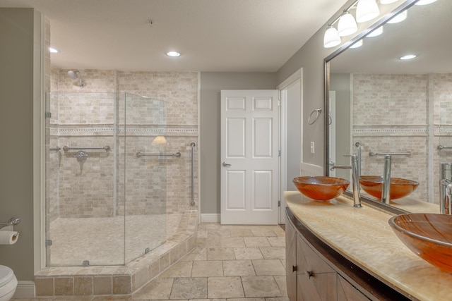 full bathroom with a stall shower, baseboards, stone tile flooring, vanity, and recessed lighting