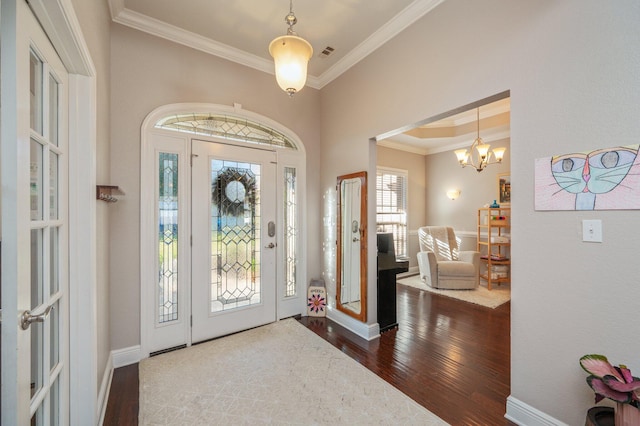 foyer entrance featuring dark wood-style floors, visible vents, an inviting chandelier, and ornamental molding