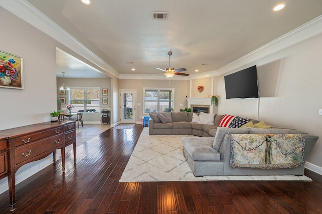 living room featuring visible vents, a fireplace, crown molding, and hardwood / wood-style floors