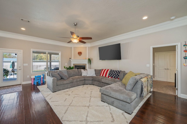 living room with visible vents, crown molding, baseboards, dark wood finished floors, and a fireplace