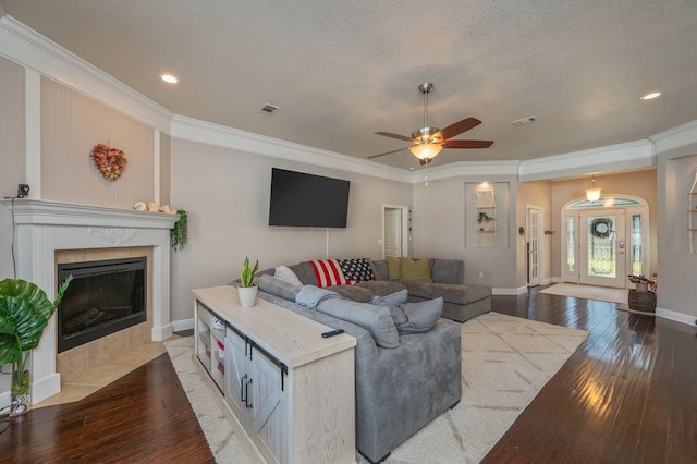 living room featuring visible vents, wood-type flooring, a textured ceiling, and crown molding