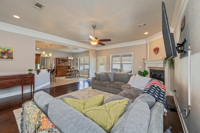 living area featuring visible vents, baseboards, ornamental molding, hardwood / wood-style floors, and a fireplace