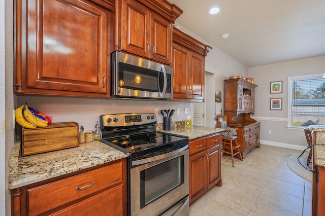 kitchen featuring light stone counters, baseboards, light tile patterned floors, and stainless steel appliances