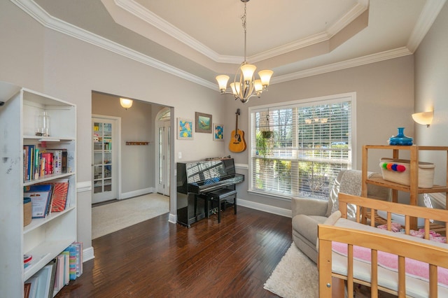 living area featuring hardwood / wood-style floors, a tray ceiling, baseboards, and a chandelier