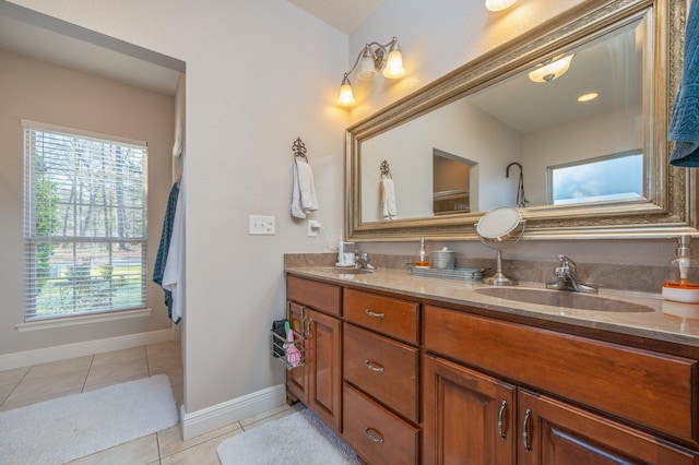 full bath featuring tile patterned flooring, double vanity, baseboards, and a sink