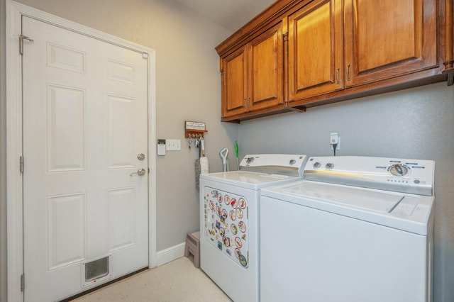 washroom with baseboards, cabinet space, and washing machine and clothes dryer